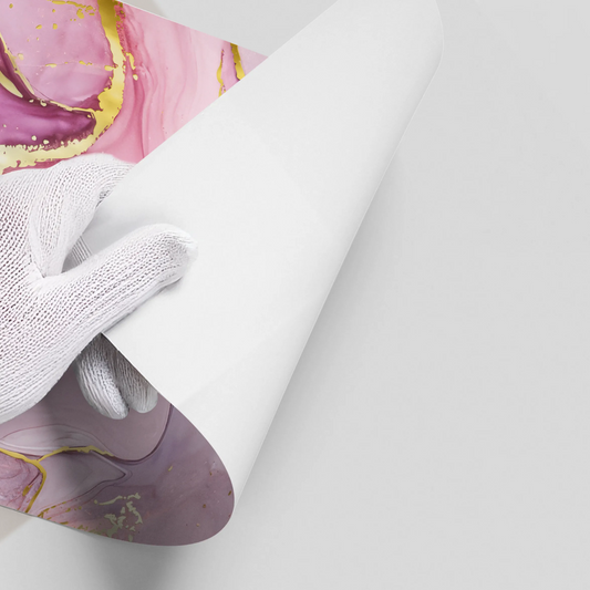 Close-up of hands in white gloves peeling back white backing of abstract pink, purple, blue, and gold ink poster material