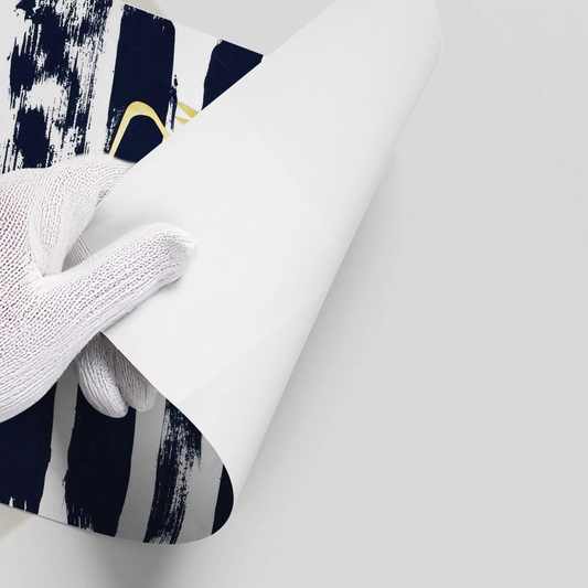 Close-up of a hand in a white glove peeling back the corner of the navy and gold flamingo poster.