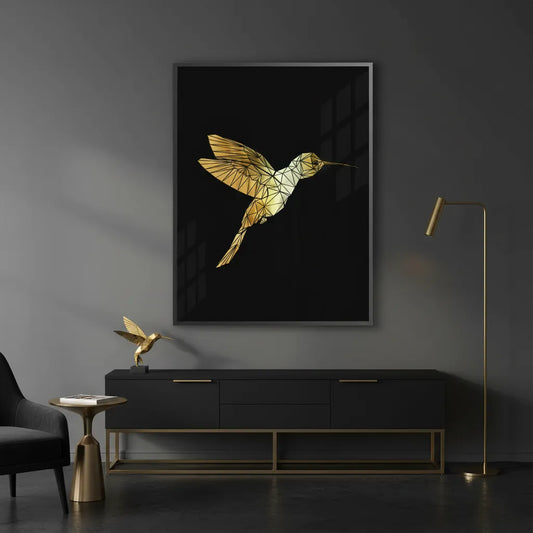Fine art print of a golden geometric hummingbird on a black background, framed in a modern room with black furniture.