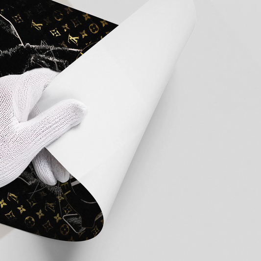 Hand in white glove peeling back the corner of the Poster material with black, white, and gold designer logo print.