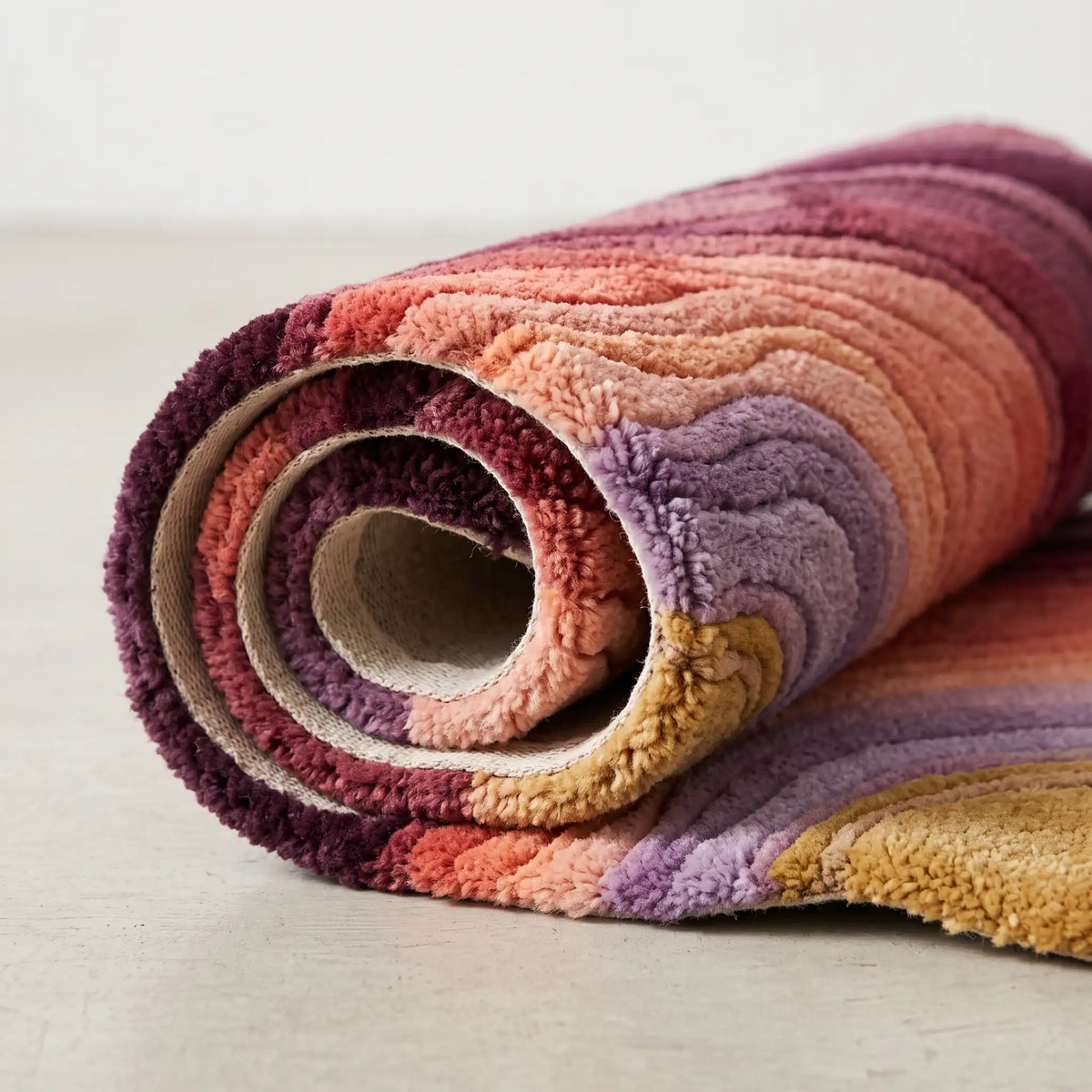Flowing Strata modern abstract rug in Plum Blush – rolled to show the backing and thickness