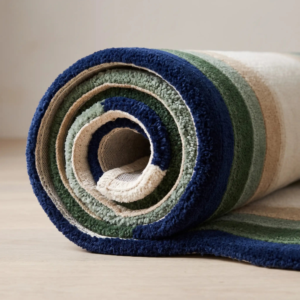 Echo Pool modern abstract rug in Navy Sage – rolled to show the backing and thickness